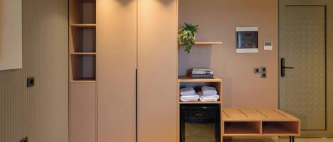 A modern room with a wardrobe, a built-in heater, a shelf with books, a plant, and a bench.