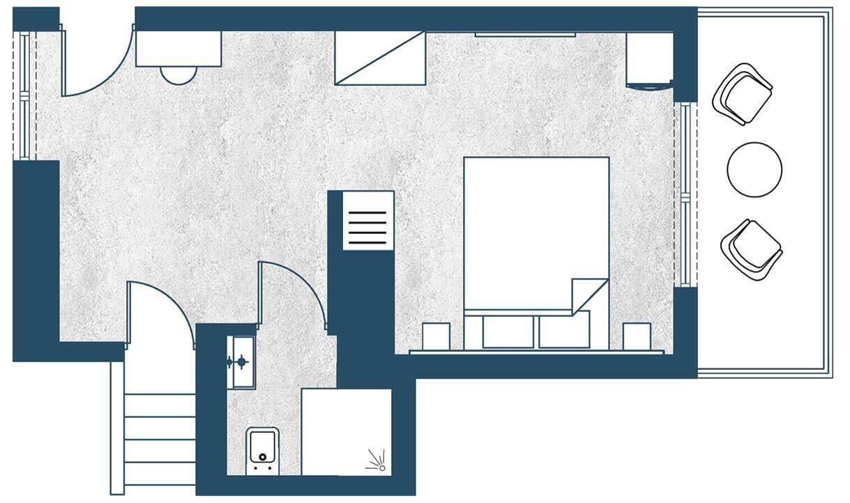 Pianta di un hotel con un'ampia sala centrale, una stanza più piccola con scrivania, un bagno e un'area salotto con tre poltrone.