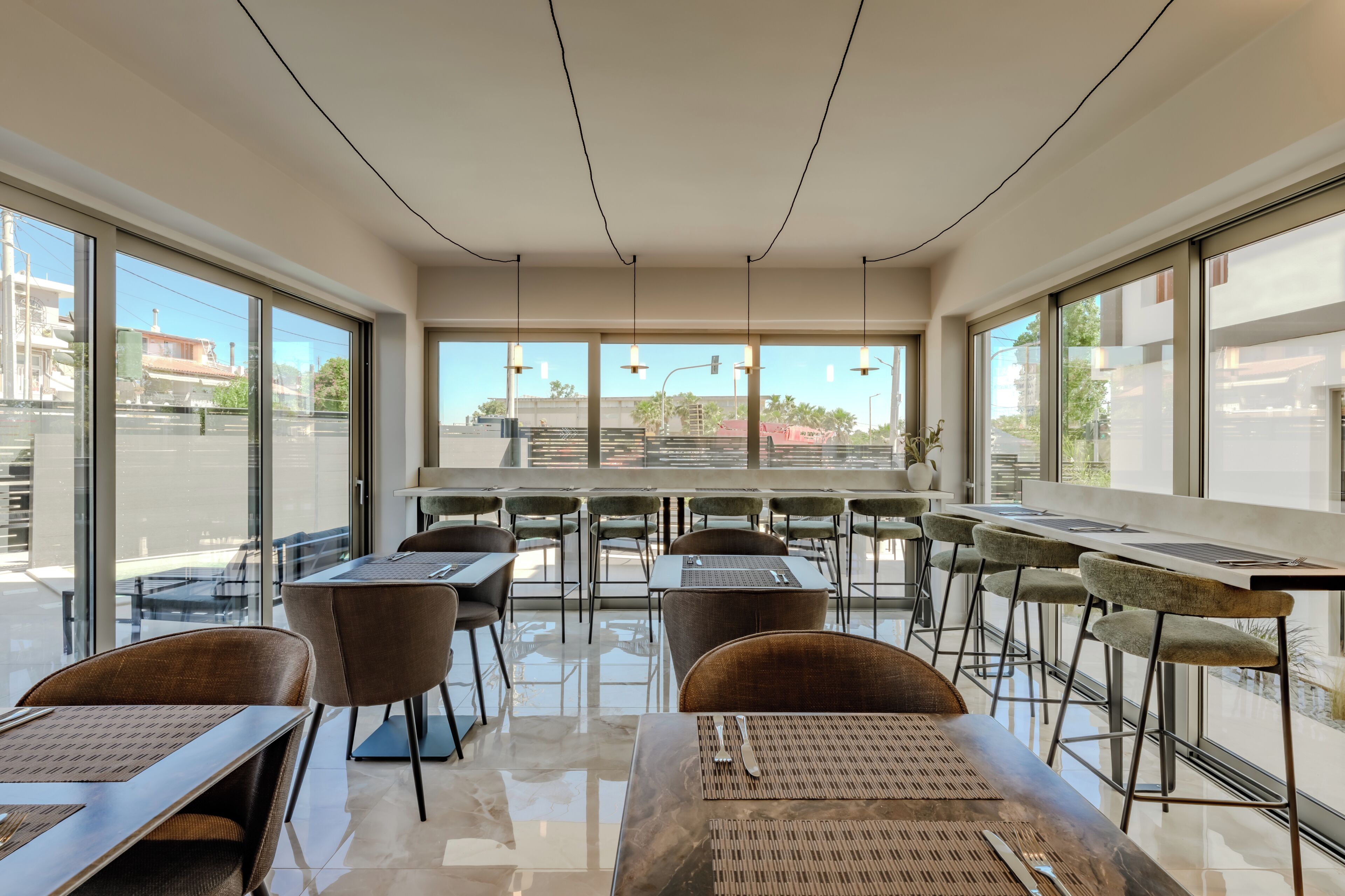 Un comedor moderno con mesas, sillas, ventanas amplias y vista a la calle.