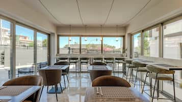 Un comedor moderno con mesas, sillas, ventanas amplias y vista a la calle.