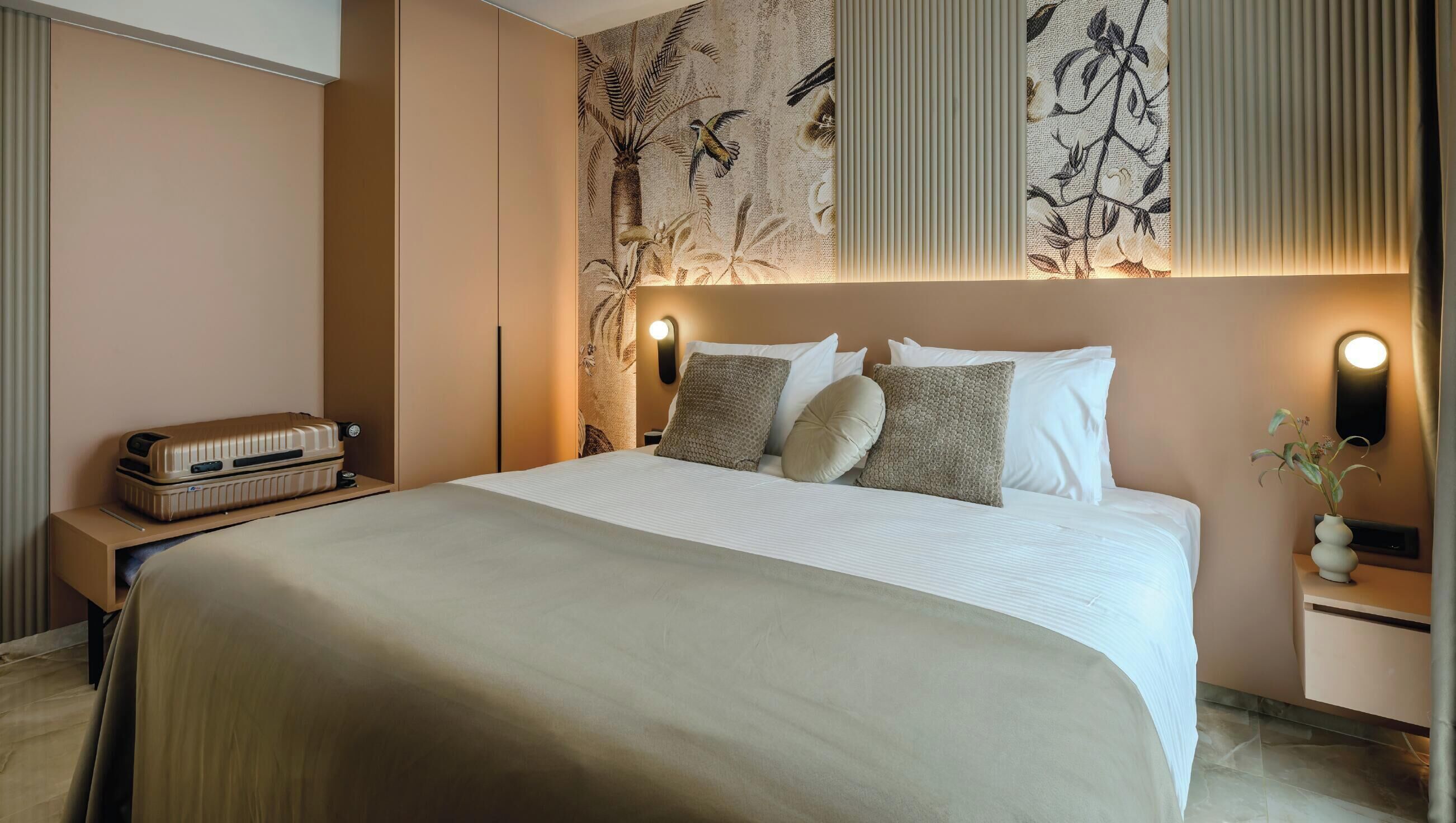 Ein Hotelzimmer mit einem großen Bett, einem Nachttischchen mit Radio, einer Wandlampe und einer dekorativen Wandverkleidung über dem Bett.