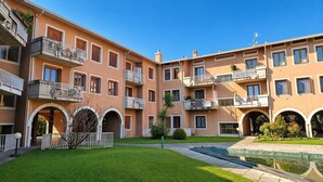 Um edifício residencial com vários andares, varandas, um pátio e uma piscina.