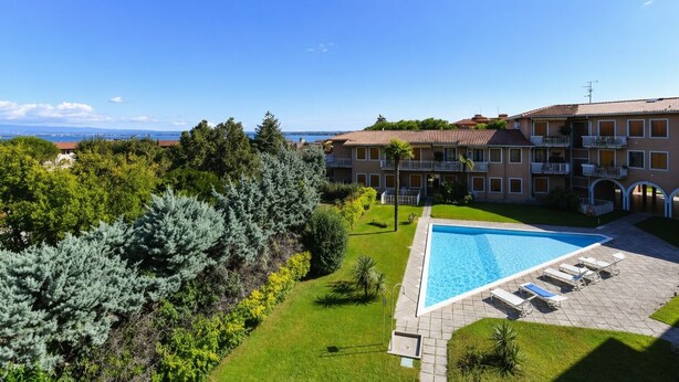 Um hotel com piscina, gramado bem cuidado e vista para o mar.