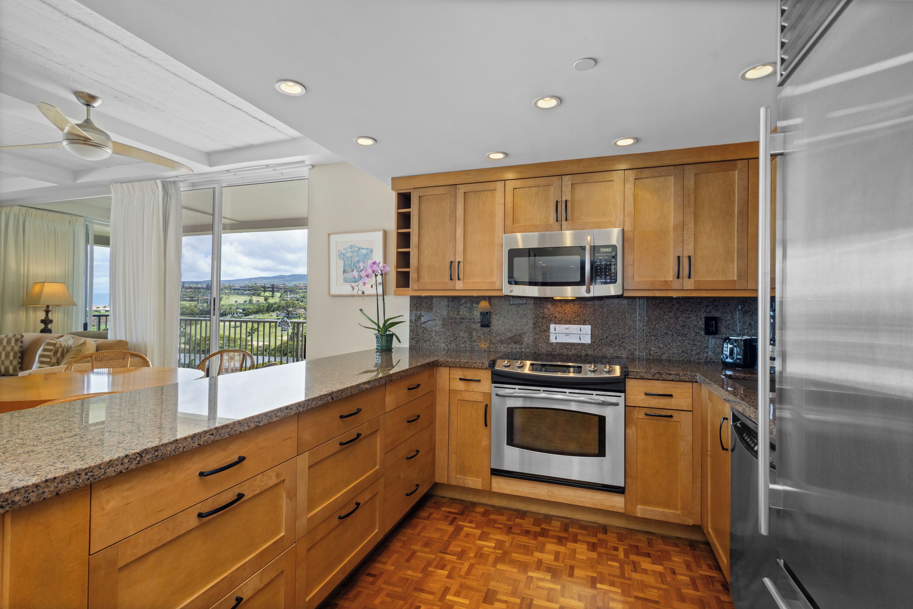 A kitchen with wooden cabinets, a stainless steel refrigerator, a microwave, and an oven.