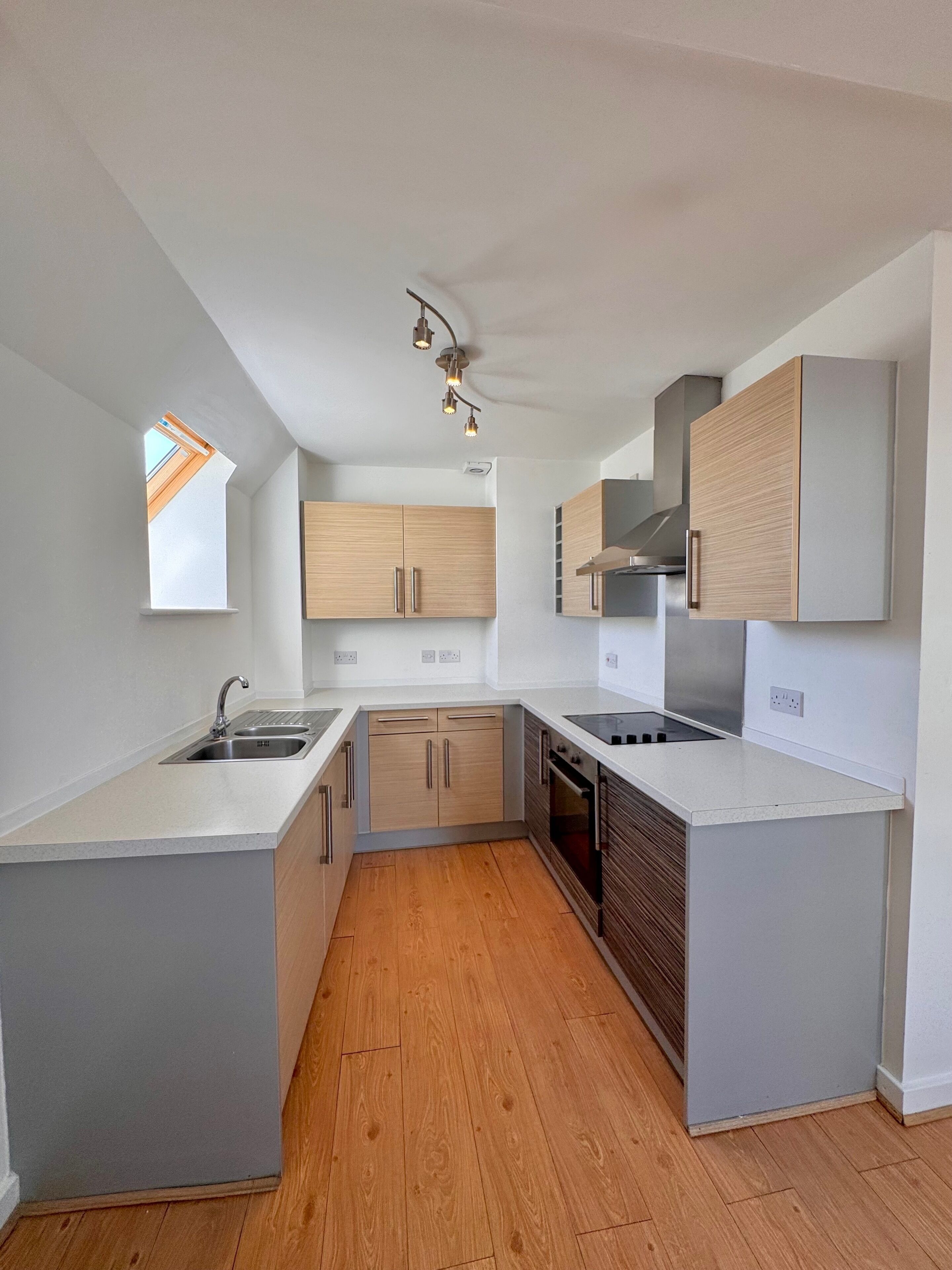 Une cuisine moderne dotée d’un îlot central, de meubles en bois et d’un four encastré.