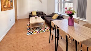 Un salon moderne avec un plafond haut, une lucarne, une grande fenêtre et un plancher en bois.