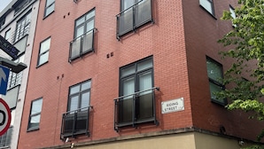 En bygning med flere etager, rød murstensfacade og mange vinduer, med skilt der viser 'Riding Street'.