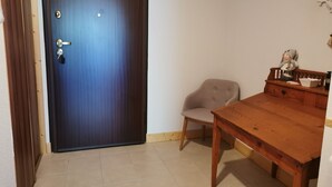 Une pièce avec une table en bois, une chaise, une porte bleue et un petit banc sur lequel est posée une figurine.