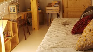 Une chambre avec un espace bureau surélevé, des meubles en bois et un lit avec des oreillers.