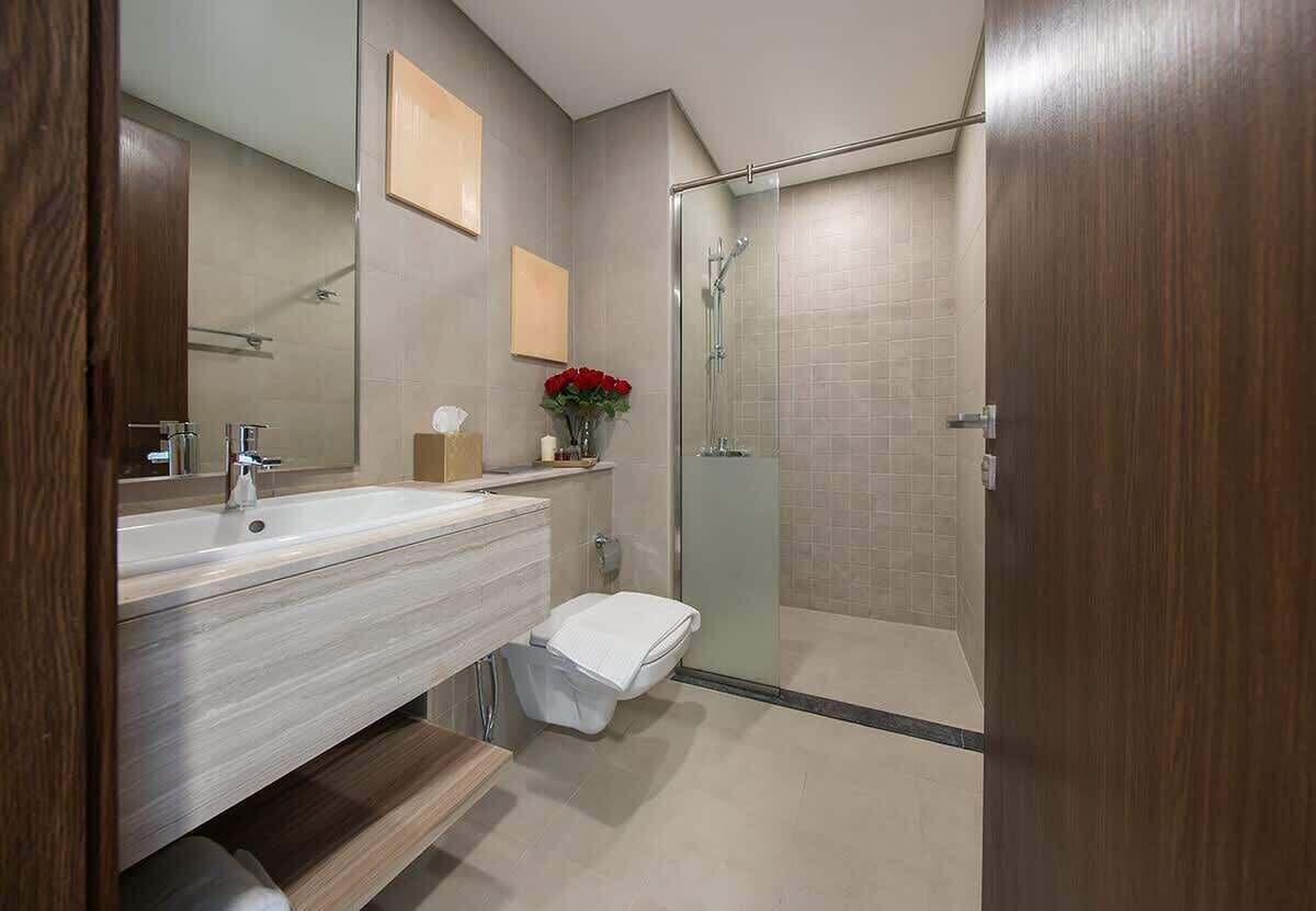Une salle de bain moderne avec un grand miroir, un lavabo, des toilettes et une douche séparée par une paroi en verre.