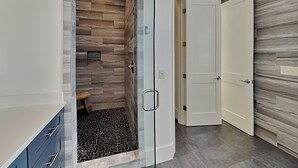 Un baño moderno con ducha, un banco y zona de ducha con mampara de vidrio.