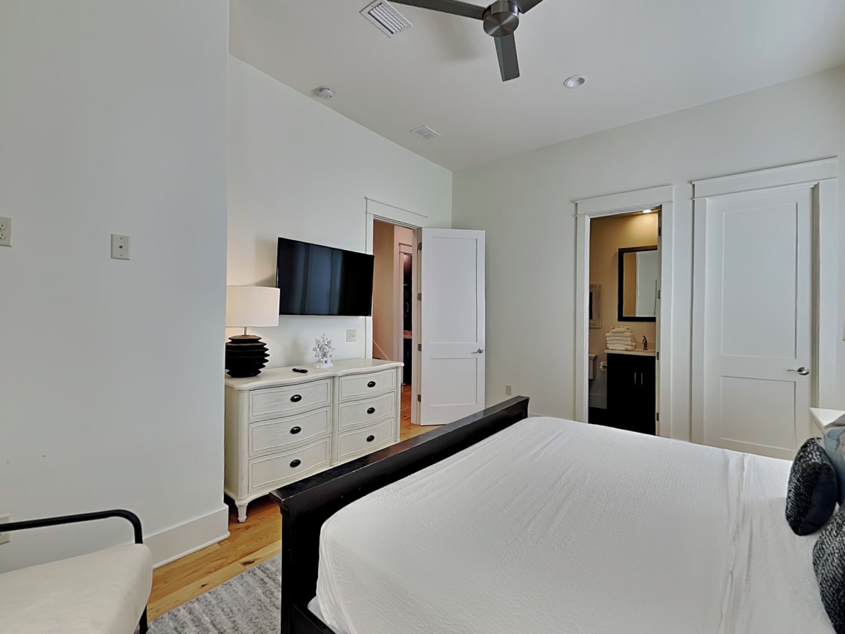 A bedroom with a bed, a dresser, a television, and a ceiling fan.
