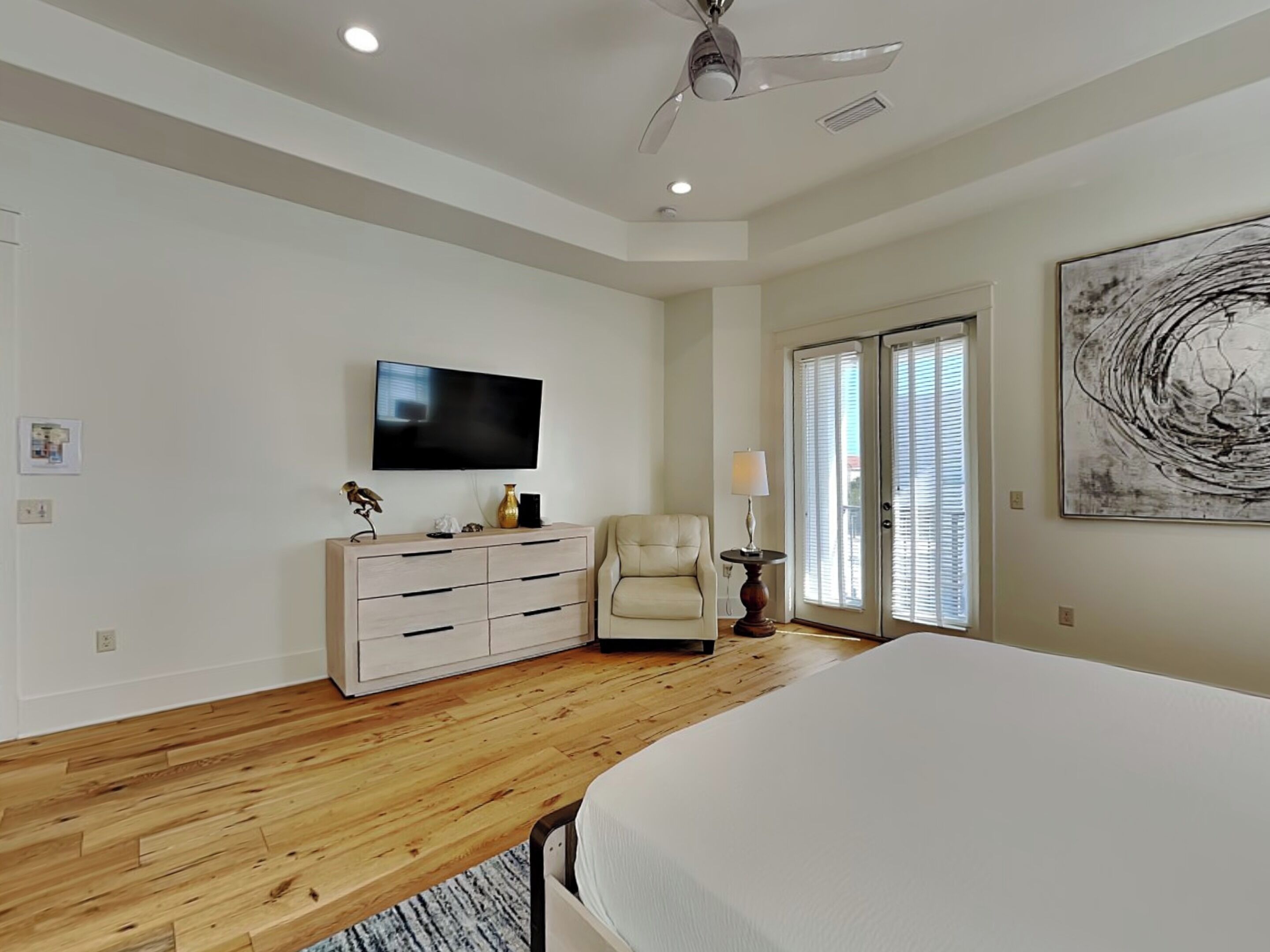 A bedroom with a bed, a TV, a chair, a dresser, and a painting on the wall.