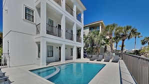 Un hotel de varios pisos con piscina, balcones y palmeras.