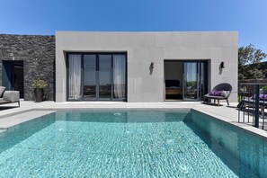 A modern building with a swimming pool, large sliding glass doors, and outdoor seating. - Las Yucas 10 by VillaGranCanaria (El Salobre)