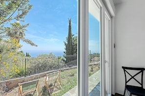 Un balcon avec vue sur la mer, une chaise noire et un chevalet vert.