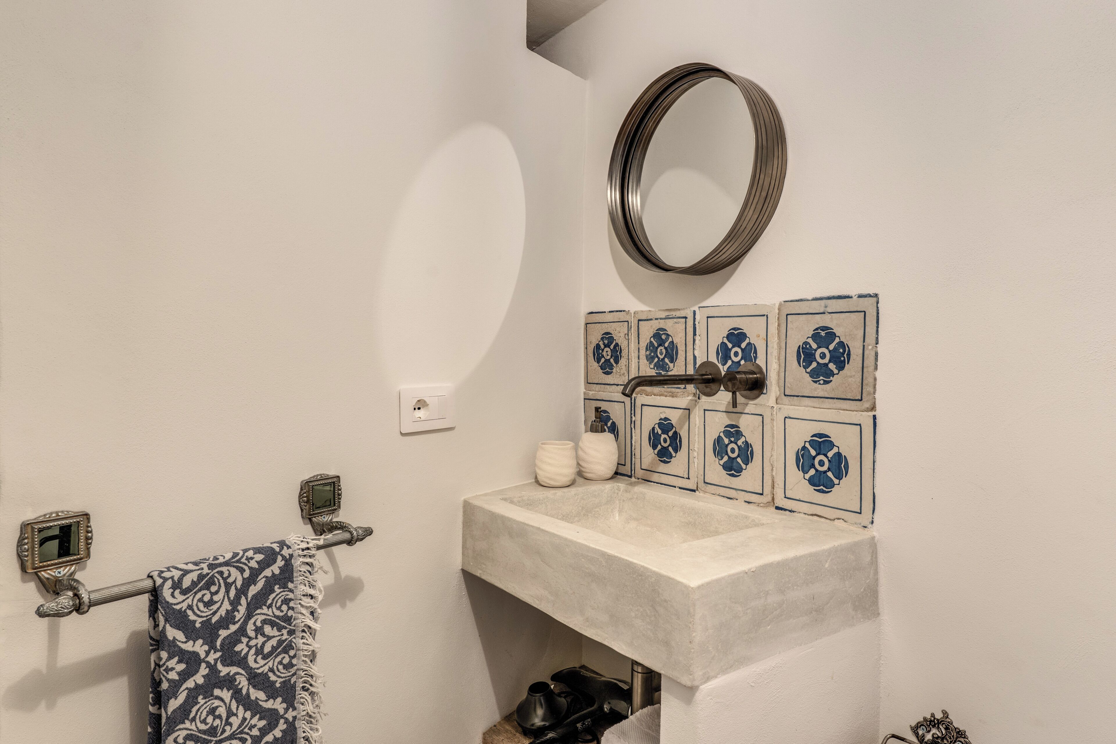 Casa de banho com lavatório, espelho, porta-toalhas e azulejos decorativos.