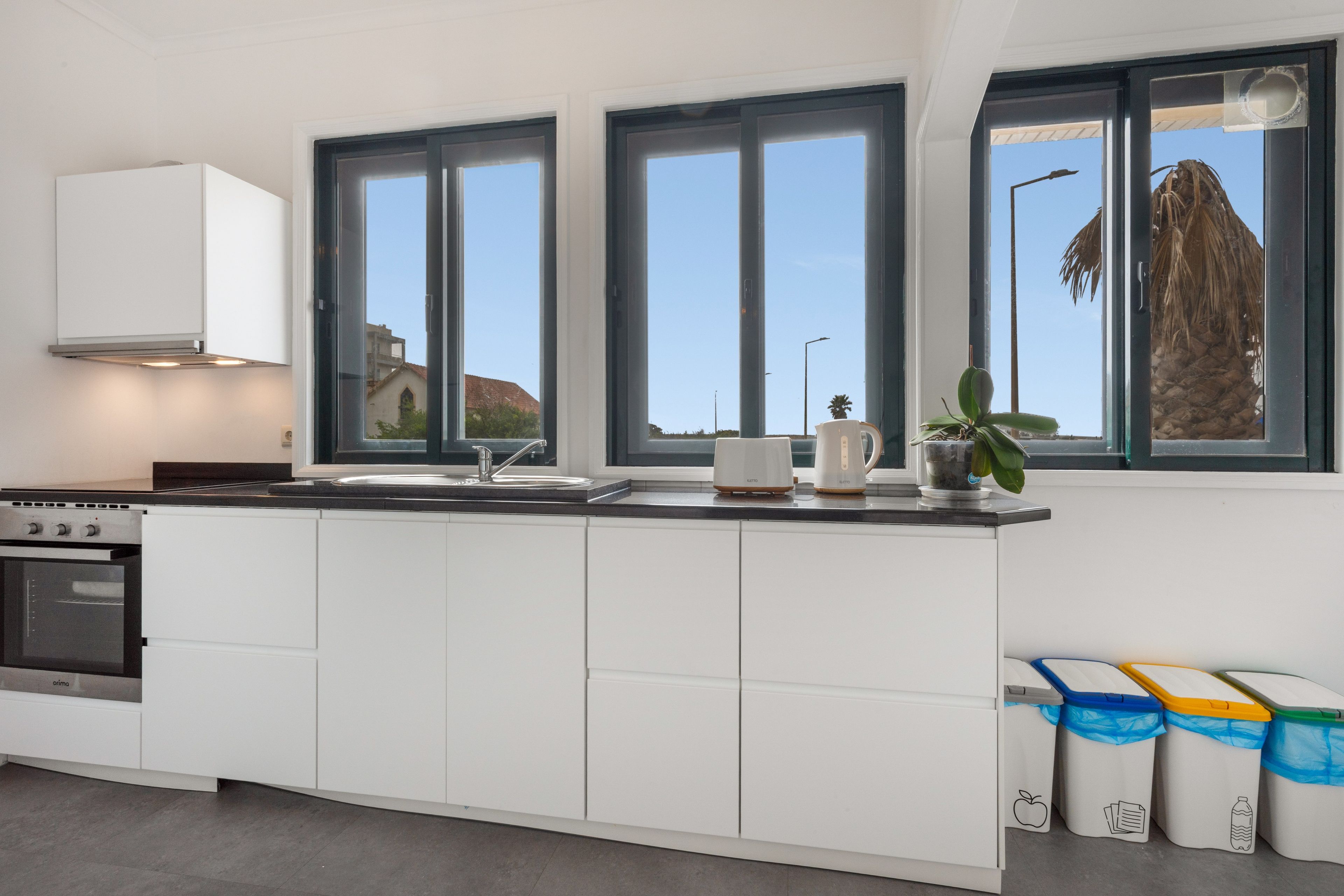 A modern kitchen with white cabinetry, a built-in oven, and a window overlooking a residential area.