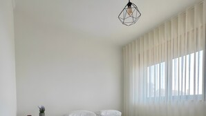 Quarto com cama, mesa de cabeceira e luminária suspensa.