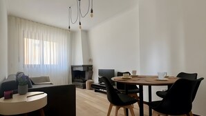 Uma sala de estar moderna com um sofá, mesa de jantar, cadeiras e lareira.