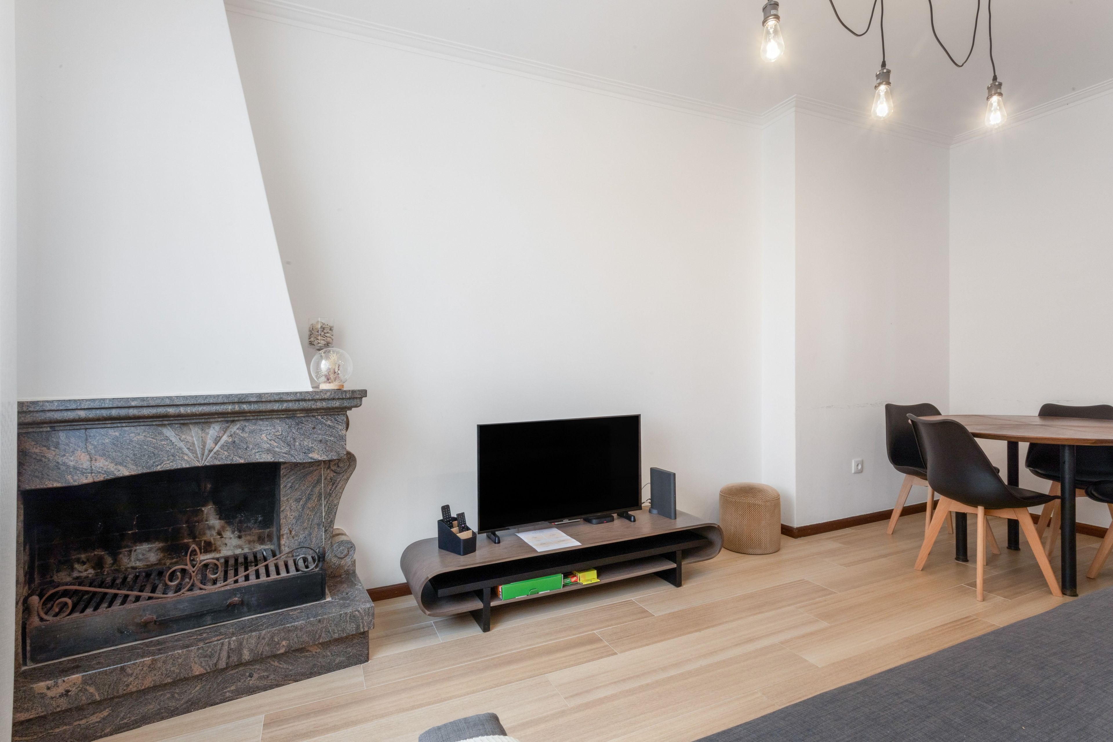Een moderne woonkamer met een open haard, een flatscreen televisie en een eethoek.