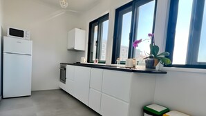 Uma cozinha moderna com armários brancos, micro-ondas embutido e janela com vista.