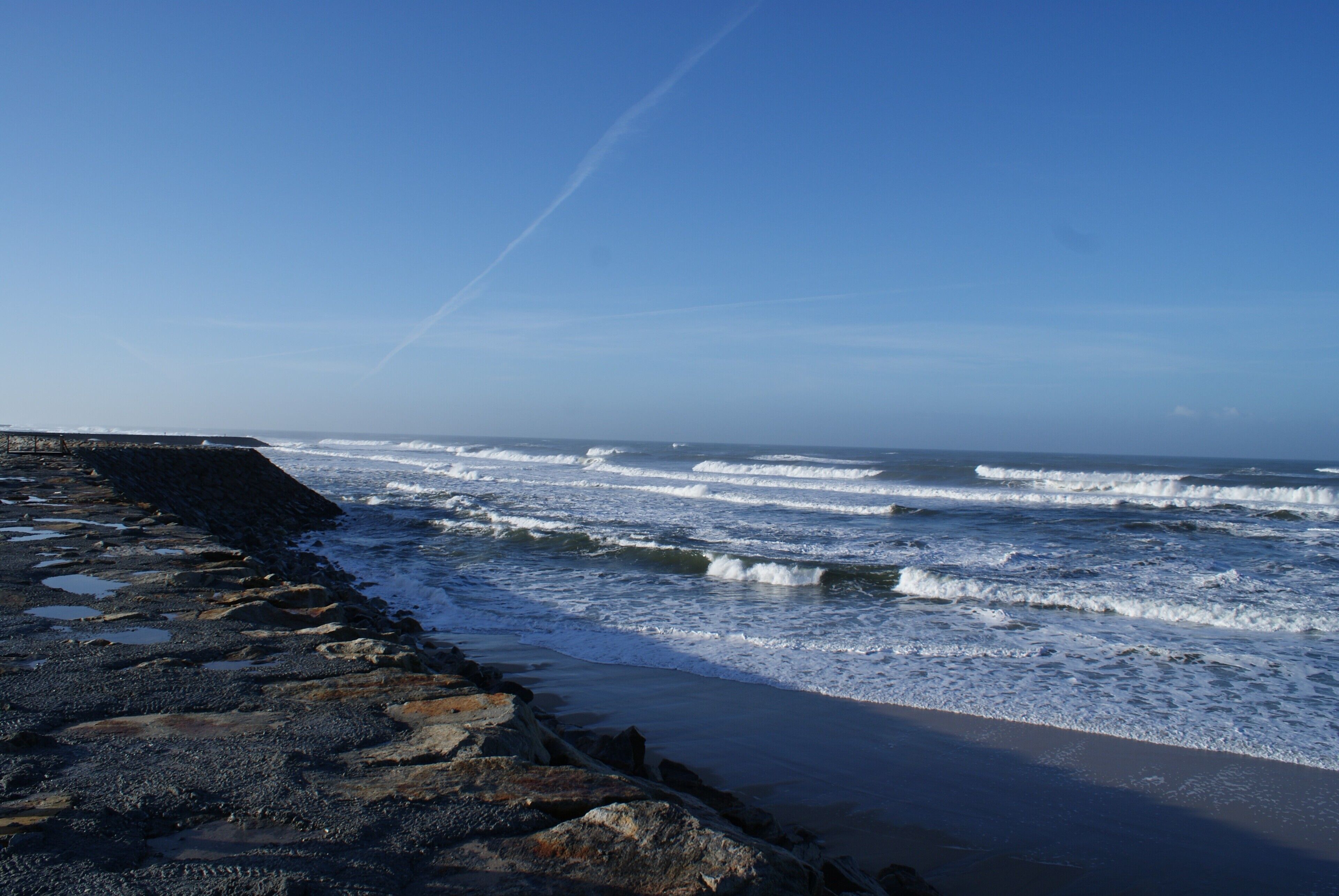 Een rotsachtige kustlijn met golven die op het strand breken.