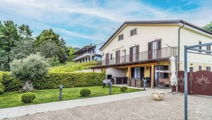 Un bâtiment à deux étages doté d’un balcon, d’un espace barbecue et d’une allée gravillonnée.