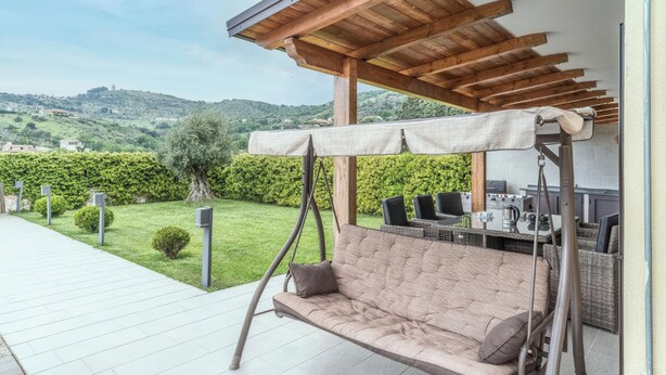 Une terrasse avec un fauteuil suspendu, du mobilier d’extérieur et une vue sur la campagne.
