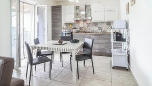Une cuisine moderne avec des meubles blancs, une table à rayures et un coin repas avec des chaises.