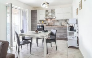 Une cuisine moderne avec des meubles blancs, une table à rayures et un coin repas avec des chaises.