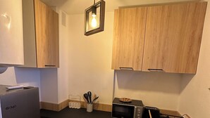 Eine kleine Küche mit Kühlschrank, Mikrowelle, Toaster und Holzschränken.