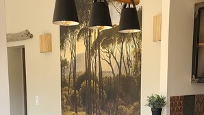 Eine Bar mit zwei hölzernen Barhocker, einer Holztresen und einem Wandbild von Bäumen.