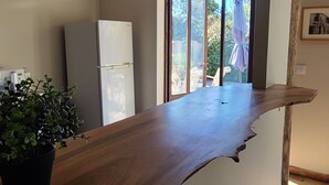 Eine Küche mit Holzarbeitsplatte, einem Kühlschrank, hängenden Pendelleuchten und einem Blumentopf.