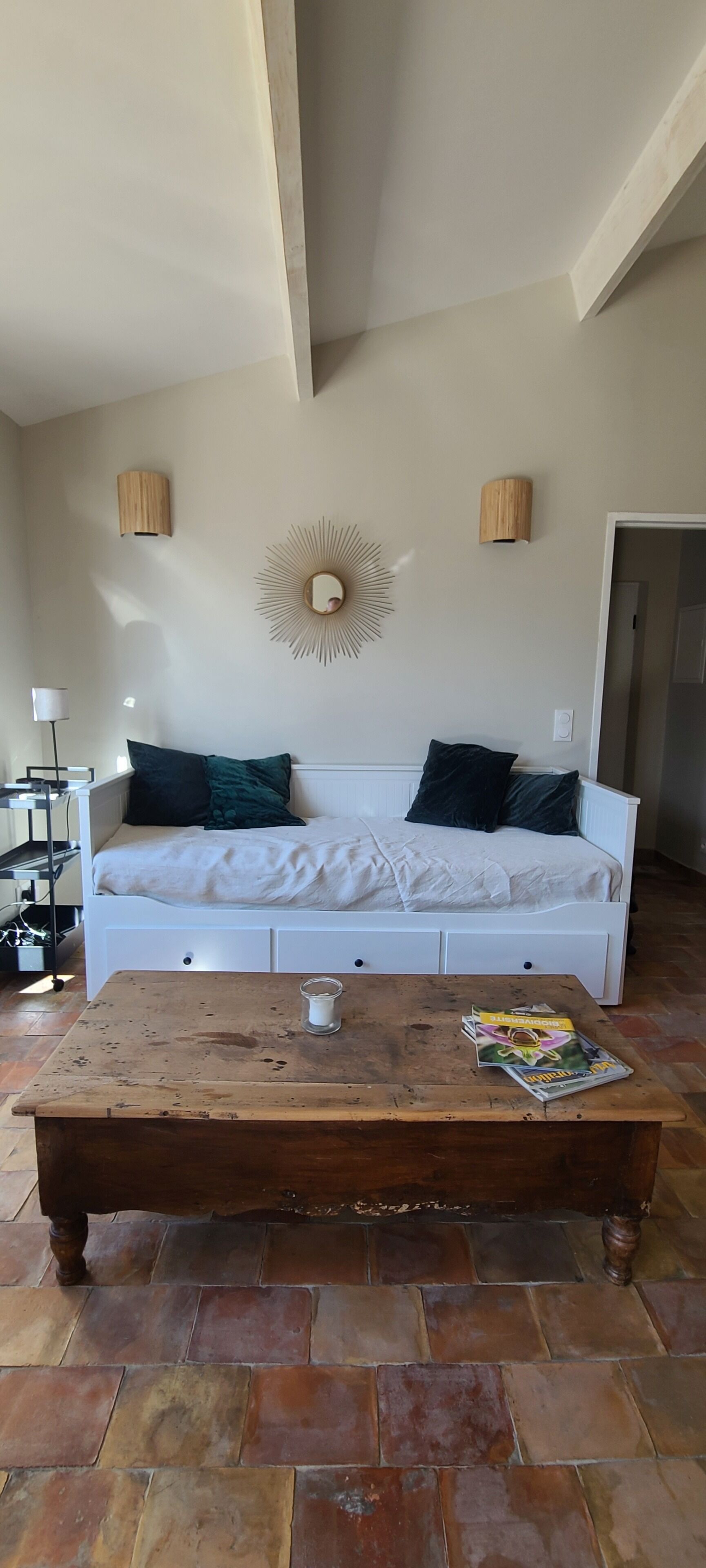 A room with a white sofa, a wooden coffee table, and a mirror on the wall.