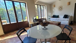 Ein Zimmer mit Esstisch, Stühlen, einer Couch und einem Fernseher.