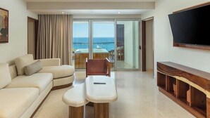 A modern living room with a sofa, a coffee table, a TV mounted on the wall, and a balcony with a view of the sea. - Two bedroom Corazon suite with hot tub, and ocean view (Cabo San Lucas)
