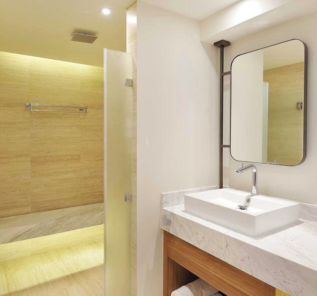 Une salle de bain moderne équipée d’une douche, d’un lavabo et d’un miroir.