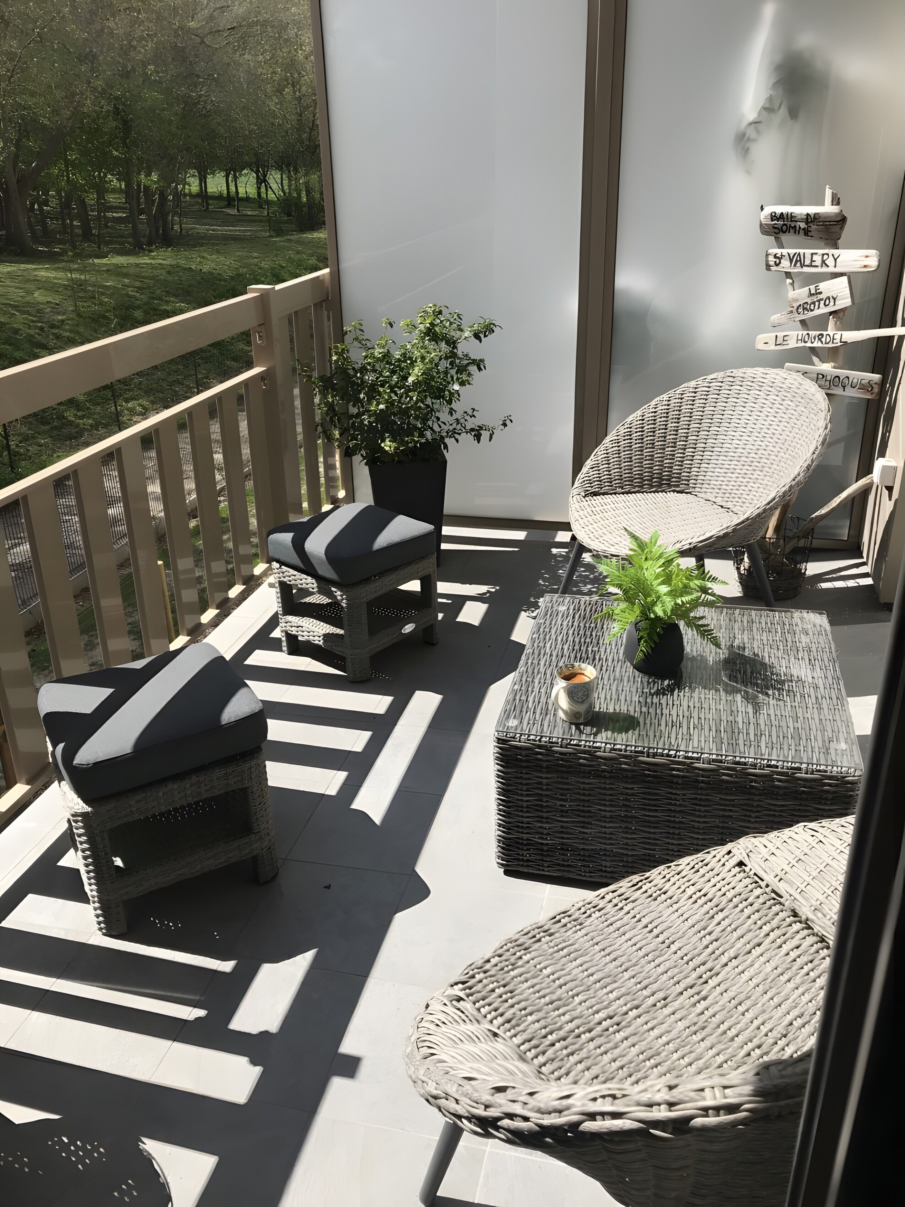 Een balkon met rieten meubilair, een potplant en richtingaanwijzingen.