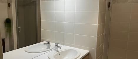 A bathroom with two sinks, a mirror, and a hanging light fixture.