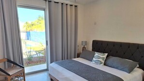 A bedroom with a bed, a chair, a lamp, and a view of the outdoors. - 1. BEAUTIFUL APARTMENT JUST A FEW STEPS FROM THE BEACH (Progreso)