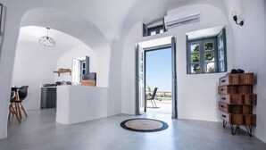 A spacious interior with a kitchen, dining area, and a view through an open door. - Noelia Suites - Cave by ΜΡS (OIA)