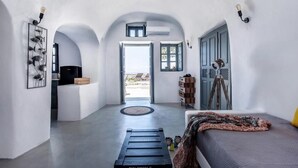 A modern room with a bed, a desk, and a view of the outdoors. - Noelia Suites - Cave by ΜΡS (OIA)