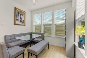 Eine moderne Küche mit Essbereich, einem Fenster mit Jalousien und einer Pflanze auf der Fensterbank.