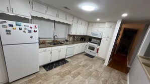A kitchen with white cabinets, a refrigerator, a microwave, and a stove. - Fabulous 3-bedroom house with AC in charming Jonesboro (Jonesboro)
