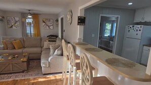 A modern living room with a sofa, coffee table, and a dining area with chairs and a long table. - Fabulous 3-bedroom house with AC in charming Jonesboro (Jonesboro)