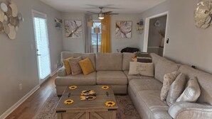 A living room with a sectional sofa, a coffee table with sunflowers, and a patterned rug. - Fabulous 3-bedroom house with AC in charming Jonesboro (Jonesboro)
