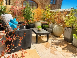A patio with wicker furniture, potted plants, and a stone floor. -    Couples Retreat in North Cumbria,w Logburner, Enclosed Terrace, Walks& Pub (Brampton)