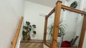 Eine Treppe mit hölzernen Geländern, einem Fischgrätparkett und einer kleinen Pflanze auf der Zwischenebene.