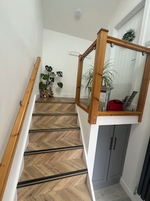 A staircase with wooden handrails, a herringbone-patterned floor, and a small plant on the landing. -    Couples Retreat in North Cumbria,w Logburner, Enclosed Terrace, Walks& Pub (Brampton)